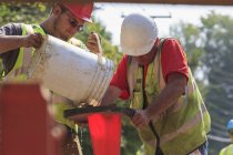 Travailleurs de la construction versant de l'eau pour amorcer une pompe — Photo de stock