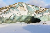 Le tracce conducono all'apertura oscura di un tunnel sotto il ghiaccio del ghiacciaio Black Rapids; Alaska, Stati Uniti d'America — Foto stock