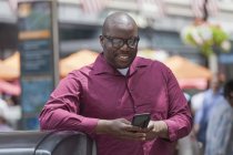 Hombre con TDAH usando un teléfono móvil en la calle de la ciudad - foto de stock