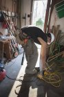 Carpintero hispano enchufando batería recargable en garaje para el hogar - foto de stock
