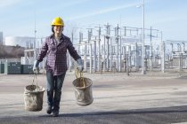 Female power engineer with canvas buckets at a power plant — Stock Photo