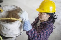 Female power engineer preparing canvas bucket in service garage — Stock Photo