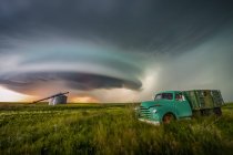 Vintage truck on farmland under a dramatic stormy sky; Moose Jaw, Saskatchewan, Canada — Stock Photo