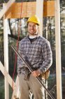 Portrait of a carpenter holding a level on house framing — Stock Photo