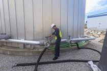 Wirtschaftsingenieur dreht Ventil an Rohr am Kraftstofftank eines Kraftwerks — Stockfoto