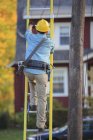Lineman climbing ladder at power pole — Stock Photo
