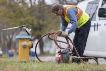 Wasserabteilungstechniker wickelt Schlauch zur Hydrantenspülung — Stockfoto