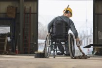 Maintenance supervisor with spinal cord injury moving tow chain in utility truck garage — Stock Photo