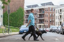 Homme ayant une déficience visuelle marchant avec son chien aidant — Photo de stock