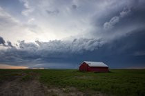 Célula de tormenta moviéndose sobre tierras de cultivo con un granero rojo; Mandíbula de alce, Saskatchewan, Canadá - foto de stock