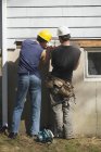 Hispanic carpenters fitting flashing under house shingles — Stock Photo