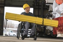 Maintenance supervisor with spinal cord injury preparing to load shielding onto utility truck — Stock Photo
