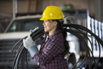 Женщина-энергетик с кабелем питания в ремонтном гараже — стоковое фото
