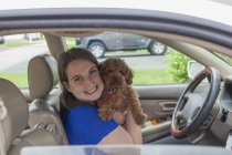 Молодая женщина с церебральным параличом держит собаку в машине — стоковое фото