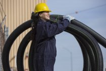 Ingeniera de potencia femenina moviendo tubos de drenaje flexibles - foto de stock