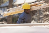 Carpenter carrying bevel cut rafters for dormer — Stock Photo