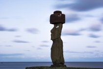 Um único moai em um fundo azul de céu, nuvens e oceano; Ilha de Páscoa, Chile — Fotografia de Stock