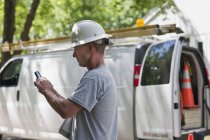 Cable installer reviewing work order for installation on smartphone — Stock Photo
