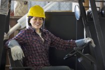 Ingénieur de puissance femelle conduisant un chariot élévateur dans le garage de service — Photo de stock