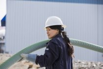 Female power engineer moving flexible pipe at power plant — Stock Photo