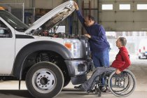 Técnico de mantenimiento automotriz y supervisor con lesión de médula espinal en garaje para camiones - foto de stock