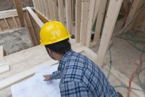 Carpinteiro revisão de planos de casa, visão traseira — Fotografia de Stock