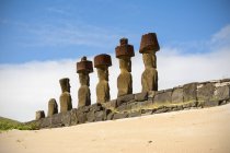 Піщаний схил спрямовує погляд на платформу і ряд з п'яти моаїв, які видно ззаду, острів Пасхи, Чилі. — стокове фото