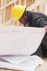Carpenter revisando planos de construção de casa no local — Fotografia de Stock