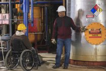 Power Plant engineers one with spinal cord injury discussing demineralization process equipment — Stock Photo