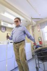 Mann mit angeborener Blindheit legt seine Wäsche in den Wäschewagen in der Waschküche — Stockfoto