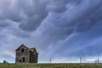 Antigua granja en las praderas bajo un cielo tormentoso; Saskatchewan, Canadá - foto de stock