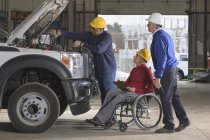 Power plant engineers one with spinal cord injury reviewing utility truck maintenance — Stock Photo