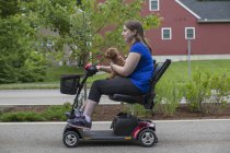 Junge Frau mit Zerebralparese auf dem Roller mit ihrem Hund — Stockfoto