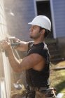 Hispanic carpenter trimming house siding for installation of new deck — Stock Photo