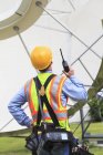 Engenheiro de comunicações usando walkie-talkie em instalação de antena de satélite — Fotografia de Stock