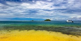 Barco amarrado frente a la costa de la isla de Malolo en el agua clara y tranquila del Pacífico Sur; Isla de Malolo, Fiji - foto de stock