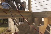 Плотник прибивает палубу к лестницам — стоковое фото