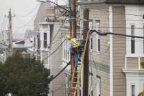 Cabo lineman avaliando a fiação de distribuição de cabos em postes na cidade — Fotografia de Stock