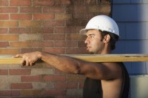 Hispanic carpenter carrying pressure treated lumber at house site — Stock Photo