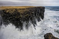 Waves splash up against the cliffs along the coast; Arnarstapi, Snaefellsnes, Iceland — Stock Photo