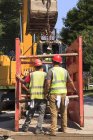 Operatore escavatore sollevamento puntellamento attaccato alla benna — Foto stock