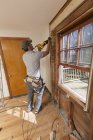 Carpinteiro hispânico usando serra recíproca para remover a janela e cortar a porta de acesso — Fotografia de Stock