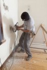 Carpinteiro hispânico usando serra circular para cortar papelão para porta do convés em casa — Fotografia de Stock