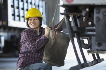 Female power engineer attaching canvas bucket to equipment truck — Stock Photo