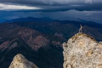 Мандрівник, що стоїть під сонцем на вершині гори Сунакпак, а грозові хмари наближаються до хребта Брукс; Аляска, Сполучені Штати Америки. — стокове фото