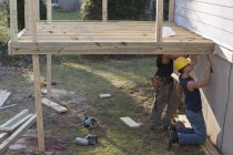 Hispanic carpenters nailing joist supports for deck construction — Stock Photo
