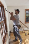 Carpinteiro hispânico removendo janela enquadrando de quarto em casa — Fotografia de Stock