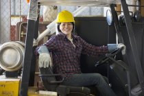 Женщина-энергетик водит вилочный погрузчик в служебном гараже — стоковое фото