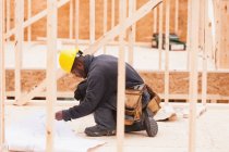 Carpenter revisando planos de construção de casa no local — Fotografia de Stock