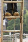 Carpinteiro em pé em uma escada, imagem cortada — Fotografia de Stock
